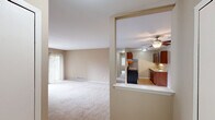 Located at 7040 Round Hill Dr in Waterford, MI, this two-bedroom, two-bathroom unit offers a well-organized single-floor layout designed for comfortable everyday living. The open-concept kitchen and living area form the heart of the home, where rich cherry wood cabinetry lines both sides of a galley-style kitchen equipped with stainless steel appliances, including a refrigerator and electric range. Light wood-style flooring runs through the kitchen, which transitions seamlessly into the carpeted living room. A ceiling fan overhead and a sliding glass door leading to a covered balcony enhance the living space, which is bathed in natural light and offers pleasant views of mature trees and the surrounding neighborhood. Both bedrooms feature soft carpeting, warm neutral-toned walls, and large windows dressed with vertical blinds that allow ample natural light. The generously sized primary bedroom provides a comfortable retreat. The two bathrooms are finished with tile flooring and warm-toned walls; one includes a full tub-shower combination with white tile surround, while the second serves as a convenient half-style bath with a vanity and sink. Throughout the unit, a cohesive warm beige palette and clean white trim create a consistent, welcoming ambiance.