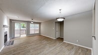 Located at 7889 Roswell Rd in Sandy Springs, GA, this single-floor residence offers a well-organized layout with a cohesive, neutral color palette throughout. The living room serves as the heart of the home, showcasing wood-look flooring, a classic fireplace with a tiled surround and white mantel, and a ceiling fan overhead. A sliding glass door opens directly to a private outdoor balcony, allowing natural light to flow in and providing views of the surrounding greenery. Adjacent to the living area, the dining space features a pendant light fixture and continues the same durable flooring, with an open sightline into the kitchen. The kitchen is thoughtfully appointed with white shaker-style cabinetry, granite-look countertops, a stainless steel gas range, and an over-the-range microwave, offering both style and functionality. The bedrooms are carpeted for comfort, each equipped with ceiling fans and ample natural light from well-positioned windows. Closet access is conveniently located within the bedrooms. The bathrooms are clean and functional, featuring white tiled tub-shower combinations with chrome fixtures. Textured ceilings are consistent throughout the home, adding a classic finishing detail to the overall design.