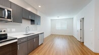 Located at 5300 E Washington St in Phoenix, Arizona, this single-floor unit offers four bedrooms and two bathrooms within a thoughtfully arranged, compact footprint. The open kitchen and living area serve as the central hub of the space, featuring light hardwood-style flooring, recessed lighting, and a bold blue entry door that adds a distinctive modern touch. The kitchen is well-appointed with dark wood-grain cabinetry, white quartz countertops, and a full suite of stainless steel appliances including a refrigerator, electric range, microwave, and dishwasher.

The bedrooms are carpeted for comfort and finished with clean white walls, offering a calm and neutral atmosphere. One bedroom includes a dedicated closet with built-in shelving, providing practical storage. Natural light filters into the bedrooms through slatted blinds on standard windows.

The two bathrooms maintain a consistent modern aesthetic, featuring hardwood-style flooring, dark wood vanities with white countertops, and chrome fixtures. One bathroom includes a full tub-shower combination. Throughout the unit, the design is clean, contemporary, and functional, making efficient use of every square foot.