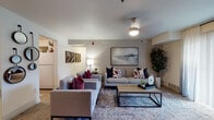 This single-floor residence offers a comfortable and thoughtfully designed layout across several well-defined living spaces. The living room serves as the heart of the home, featuring warm neutral-toned walls, wood-style flooring, and a large sliding glass door dressed with sheer curtains that invite abundant natural light and provide views of surrounding greenery. The open, airy atmosphere is complemented by a dedicated media wall with ample storage.

The kitchen is equipped with warm wood cabinetry, light countertops, and a full suite of appliances including a range, over-the-range microwave, dishwasher, and refrigerator — all set atop durable wood-style flooring for easy maintenance.

Two bedrooms offer restful retreats, each with plush carpeting and windows that allow natural light to filter through. The primary bedroom features a large window with outdoor views, while the secondary bedroom includes stylish ombre curtains and a closet with panel doors.

The bathroom is clean and functional, with warm wood vanity cabinetry, a shower-tub combination with a curtain, and light wood-style flooring. A separate utility space provides wire shelving, an electrical panel, and hookups for laundry, adding everyday convenience to this well-rounded residence.