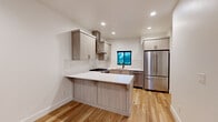 Located at 6312 W State St in Boise, Idaho, this two-story property showcases a modern aesthetic with thoughtfully selected finishes throughout. The design is characterized by a neutral palette of whites and soft grays, creating a bright and cohesive atmosphere across both floors.

The kitchen serves as a central highlight, featuring flat-front cabinetry in a warm light wood tone, crisp white quartz countertops, and a peninsula that provides additional prep space and seating. Stainless steel appliances, including a full-size refrigerator and gas cooktop, complement the space, while a subway tile backsplash adds textural detail. A black-framed window above the sink introduces natural light and outdoor views.

Living areas are finished with light-toned hardwood flooring that lends warmth and continuity throughout the main level. Recessed lighting illuminates each room evenly, and black-framed sliding glass doors and windows provide a modern contrast to the white walls. Bedroom spaces are carpeted in a neutral tone for comfort and feature windows that bring in natural light.

The bathroom includes a tiled tub-shower surround with oversized white tile and matte black fixtures, offering a clean, contemporary look. Overall, the space presents a well-finished, move-in ready environment with consistent modern detailing.