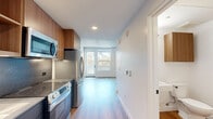 Located at 932 Torrance St in San Diego's vibrant Mission Hills neighborhood (92103), this efficiently designed single-floor unit makes smart use of its compact footprint. The open layout connects the living area and kitchen in a seamless flow, maximizing functionality without sacrificing style.

The kitchen is a standout feature, showcasing contemporary design with warm wood cabinetry, open shelving, dark lower cabinets, and a stone-look backsplash. Stainless steel appliances — including an electric range with oven and an over-the-range microwave — are paired with light quartz countertops and an undermount sink, creating a sleek, modern workspace.

The living area is bright and minimal, benefiting from large windows that invite natural light and lend an airy, open feel. Exposed concrete ceiling elements add an industrial character, contrasted by crisp white walls and warm-toned hardwood flooring that runs throughout the entire unit, lending visual continuity and warmth.

The bathroom is clean and simply appointed, with white walls, matte black hardware accents, and the same warm wood flooring extending from the main living space, maintaining a cohesive aesthetic. The overall design is modern, understated, and well-suited for efficient urban living in one of San Diego's most walkable neighborhoods.
