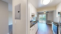 Located at 40777 High St in Fremont, California, this one-bedroom, two-bathroom residence offers a well-organized single-floor layout designed for comfortable everyday living. The galley-style kitchen is outfitted with white shaker cabinetry, dark granite countertops, a stainless steel refrigerator, and a built-in dishwasher. The kitchen flows naturally toward the living area, which features light wood-style flooring, neutral warm-toned walls, and a textured ceiling. A large sliding glass door opens to a private balcony, filling the space with natural light and outdoor views of surrounding greenery. A separate window in the living room further enhances the bright, airy atmosphere. The bedroom is a generously proportioned retreat finished with plush carpeting, a ceiling fan, and a sliding-door closet with built-in shelving for ample storage. Both bathrooms feature wood-style flooring and clean, functional finishes. A hallway connects the main areas of the residence, maintaining a logical and efficient flow throughout. The overall ambiance is calm and neutral, offering a versatile canvas well-suited to a variety of interior styles.