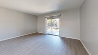 Located at 8911 Northeastern Blvd NE in Albuquerque, NM, this one-bedroom, two-bathroom unit offers a well-organized single-level layout with a clean, modern aesthetic throughout. Light wood-style flooring runs continuously across the living areas, complementing the neutral gray and white color palette that gives the space a bright, cohesive feel.

The kitchen is designed for functionality, featuring gray lower cabinetry paired with white upper cabinets, white countertops, and black stainless appliances including an electric range and dishwasher. A peninsula with a single-basin sink connects the kitchen to the living area, and pendant lighting adds a polished touch. The kitchen opens through a pass-through to the living room, which is anchored by a sliding glass door leading to a private balcony with outdoor views.

The bedroom is a comfortable, well-proportioned space with a ceiling fan, a natural light-filled window, and light wood-style flooring. Both bathrooms are finished in a consistent modern style, with gray vanity cabinetry, white countertops, large mirrors, and light tile flooring. One bathroom includes a full tub-shower combination with a bright white surround. Textured ceilings are present throughout, adding a classic touch to the overall interior design.