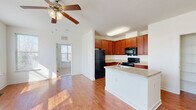 This single-floor, 5-bedroom, 2-bathroom home offers a well-designed layout that balances communal living and private spaces. The open-concept kitchen and living area serves as the heart of the home, featuring rich cherry wood cabinetry, granite-look countertops, black appliances including a range, built-in microwave, and refrigerator, plus a peninsula with a sink that provides additional workspace and casual seating. Warm hardwood-style flooring flows throughout the main living areas, complemented by a ceiling fan that adds both comfort and charm.

A bright hallway connects the bedrooms, which feature a mix of hardwood-style and plush carpeted flooring. Several bedrooms receive abundant natural light through large windows with views of surrounding trees. The primary bedroom is well-proportioned and includes a ceiling fan. Additional bedrooms offer closets with built-in shelving for organized storage. Two bathrooms are finished with light tile flooring, wood-tone vanities, and clean white fixtures. The home also includes two closets for additional storage. Clean white walls and consistent finishes throughout give the space a cohesive, move-in-ready aesthetic.
