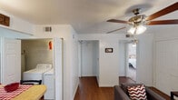 This single-floor residence offers a thoughtfully arranged layout that balances comfort and functionality across its living spaces. The living room serves as the heart of the home, featuring rich hardwood flooring, a ceiling fan with integrated lighting, large windows that invite natural light and outdoor views, and a distinct accent wall that adds a modern touch to the otherwise neutral palette. Track lighting provides additional illumination, making the space versatile and welcoming.

The kitchen is efficiently designed with white cabinetry, a double sink, white appliances, and light countertops. It connects seamlessly to a dining area, creating an ideal setting for shared meals. A convenient in-unit laundry area with a full-size washer and dryer is tucked neatly nearby, adding a practical amenity to daily living.

The bedrooms are carpeted for comfort and each features ceiling fans, generous mirrored sliding-door closets, and windows dressed with blinds that allow for natural light control. One bedroom includes a built-in desk, making it well-suited as a study or workspace. The overall aesthetic throughout the residence is clean and bright, with white walls providing a versatile backdrop that complements each room's individual character.