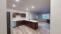 Located in Cedar Rapids, Iowa, this single-floor residence offers a thoughtfully designed layout with modern finishes and functional living spaces throughout. The heart of the home is a generously sized kitchen equipped with rich dark-wood cabinetry, white quartz countertops, stainless steel appliances — including a refrigerator, range, microwave, and dishwasher — and light wood-style vinyl plank flooring. The kitchen opens toward the living area, which features large windows that allow ample natural light and views of the surrounding neighborhood. The living space accommodates a comfortable seating arrangement and is finished with durable hard-surface flooring. Bedrooms are carpeted for warmth and comfort, with large windows providing additional natural light and baseboard heating for year-round comfort. The bathroom features dark wood cabinetry with white countertops, matching the kitchen's aesthetic, and includes a shower/tub combination. A dedicated in-unit laundry room with a washer and dryer hookup offers added convenience. Additional storage is provided through a walk-in closet with wire shelving. The unit also includes a walk-in storage closet with carpeted flooring and wire shelving systems, ideal for organizational needs.