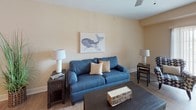 This single-floor residence offers a well-organized layout that balances comfort and functionality across its living spaces. The open-concept living and dining area serves as the heart of the home, featuring wood-style flooring, warm neutral wall tones, and a ceiling fan overhead. A sliding glass door fills the living room with natural light while providing outdoor access, and a dedicated dining nook accommodates a round table with wicker seating beneath a large decorative wall clock.

The kitchen is outfitted with rich cherry wood cabinetry, granite-style countertops, and a full suite of stainless steel appliances including a gas range, built-in microwave, and refrigerator. Wood-style flooring continues throughout this space for a cohesive look.

The primary bedroom features plush carpeting, natural light from dual windows, and convenient access to an in-unit laundry area with washer and dryer. A spacious walk-in closet with wire shelving provides ample storage. The en-suite bathroom includes a walk-in shower, a rich wood vanity with a light stone countertop, and tile flooring.

The second bedroom offers a cozy, well-proportioned layout with carpeted floors. A second full bathroom mirrors the finishes of the primary bath and includes a shower-tub combination.