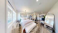 Located at 615 Jawdin Ave in Richland, WA, this efficiently designed studio offers a single-floor open-plan layout that maximizes every square foot. The main living area is bathed in natural light from large windows and features warm-toned hardwood-style flooring throughout, white walls, and recessed lighting that enhance the bright, airy atmosphere. A freestanding white open-shelf unit serves as a clever room divider, visually separating the sleeping area from the living space while maintaining an open feel. The sleeping nook is anchored by a pendant chandelier and benefits from views to the outside. The living area includes a cozy seating arrangement accented by a curated gallery wall and a sliding barn door that adds a modern-industrial touch. The compact kitchenette is outfitted with white cabinetry, a subway tile backsplash, and black appliances, seamlessly integrated into the open layout. The bathroom is a design standout, featuring floor-to-ceiling white hexagonal mosaic wall tiles, a bold star-patterned floor tile, a trough-style sink, round mirror, and a curtained shower — combining classic and contemporary aesthetics. Overall, this studio presents a cohesive, stylish interior well-suited for comfortable single-occupant living.