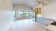 Located in the charming coastal community of Cannon Beach, Oregon, this thoughtfully designed 2-bedroom, 2-bathroom single-floor home offers a clean, modern aesthetic with high-quality finishes throughout. The open-concept living, dining, and kitchen area serves as the heart of the home, highlighted by soaring vaulted ceilings and a bank of large black-framed windows that frame verdant hillside views and flood the space with natural light. Light-toned hardwood flooring runs continuously throughout, enhancing the bright, airy atmosphere. The kitchen features two-tone cabinetry in sage and warm tan, white subway tile backsplash, stainless steel appliances including a gas range and French door refrigerator, and a dedicated pantry for added storage. Both bedrooms are well-proportioned, each featuring clerestory windows that bring in additional light, and sliding closets with built-in rods. The primary bedroom includes a private en-suite bathroom. Both bathrooms are finished in crisp white tile and offer frameless sliding glass enclosures — one with a walk-in shower and one with a shower/tub combination. A dedicated laundry room, hallway, and entrance complete this efficiently designed home.