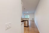This single-floor residence features a clean, modern design with a neutral color palette and consistent finishes throughout. The kitchen is well-appointed with a full suite of stainless steel appliances, including a range, over-the-range microwave, refrigerator, and dishwasher. White shaker-style upper cabinets contrast with dark lower cabinetry, complemented by light countertops and a mosaic tile backsplash. A pendant light fixture and a window over the sink provide natural light to the space.

The kitchen flows into an open living area finished with warm hardwood-style flooring, large windows with blinds, and a sliding door that allows natural light and outdoor views of surrounding greenery. The bedrooms feature patterned carpet flooring and windows framing leafy outdoor scenery, contributing to a calm atmosphere.

Two bathrooms serve the unit; one includes a soaking tub and shower combination with gold-toned fixtures, a dark-cabinet vanity with a white countertop, and light tile flooring. The second bathroom offers a similarly styled vanity. Throughout, the space maintains a consistent modern aesthetic with clean white walls, updated hardware, and quality finishes.