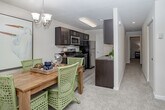 This single-floor residence in Mays Landing, NJ offers a well-designed, open layout that connects key living spaces seamlessly. The kitchen is outfitted with dark espresso cabinetry, granite-style countertops, stainless steel appliances including a gas range and built-in microwave, and light wood-style flooring that adds a clean, contemporary feel. A louvered pantry door provides additional storage convenience. Adjacent to the kitchen, the dedicated dining area features a chandelier overhead and large windows dressed with sheer curtains, filling the space with natural light. The living room is a standout, boasting soaring ceilings, a graceful arched window, and plush carpeting that extends throughout the main living areas, creating a warm and inviting atmosphere. A central hallway connects the bedrooms with ease. The primary bedroom is a serene retreat with soft carpeting and a connected bathroom featuring dark vanity cabinetry, granite countertops, and a sliding glass shower enclosure with wood-style tile flooring. An additional bedroom includes a roomy sliding-door closet. The overall palette of neutral tones, abundant natural light, and thoughtful layout make this a comfortable and functional single-level home.