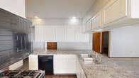 Located at 5680 Hibernia Dr in Columbus, Ohio, this single-floor home offers a practical and comfortable layout with two bedrooms and three bathrooms. The kitchen is a standout feature, appointed with crisp white cabinetry, granite-style countertops, and a full suite of black appliances including a gas range, over-the-range microwave, dishwasher, and refrigerator. A double stainless steel sink and recessed lighting complete the well-organized space. The kitchen flows into a hallway that connects the main living areas, with wood-look flooring running throughout. The living room is warm and inviting, centered around a wood-burning fireplace framed in wood trim, with large windows dressed in vertical blinds that bring in natural light and views of the surrounding greenery. Both bedrooms are carpeted and feature ceiling fans with lights, ample natural light, and direct access to bathrooms. The primary bedroom offers generous space and an en-suite bathroom complete with a soaking tub, shower, single vanity, and wood-look flooring. Additional bathrooms include a vanity with large mirror and cabinet storage. Two closets and a dedicated hallway enhance the home's storage and functionality throughout.