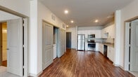 This single-story unit in Douglasville, Georgia offers a well-organized, open-concept layout with modern finishes throughout. The kitchen is a functional centerpiece, featuring white shaker-style cabinetry with brushed metal hardware, granite-look countertops, and a full suite of stainless steel appliances including a refrigerator, range, microwave, and dishwasher. Rich, dark hardwood-style flooring extends through the kitchen and main living areas, creating a cohesive and clean aesthetic.

The living area flows directly from the kitchen, providing an open, airy feel with recessed lighting overhead. Two bedrooms are finished with neutral wall-to-wall carpet, ceiling fans, and windows fitted with blinds that allow natural light while maintaining privacy.

Two bathrooms serve the unit, each with wood-style flooring, white vanity cabinetry, and light stone-toned countertops. One bathroom includes a walk-in closet with wire shelving, while the other features a soaking tub and additional storage. A dedicated laundry area with hookups adds everyday convenience. Overall, the unit presents a clean, contemporary atmosphere suited to comfortable, practical living.