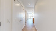 Located on the 32nd floor at 201 10 Ave SE in Calgary's vibrant Beltline district, this one-bedroom, one-bathroom unit offers a thoughtfully designed layout with contemporary finishes throughout. Light wood-tone flooring runs continuously across the entire space, complementing the clean white walls and creating a cohesive, modern aesthetic.

The entry hallway provides a well-organized introduction to the unit, flanked by a large closet with floor-to-ceiling sliding doors. The hallway leads to an open living area anchored by expansive floor-to-ceiling windows that frame striking panoramic views of the downtown Calgary skyline, flooding the space with natural light.

The kitchen is outfitted with flat-front wood-grain cabinetry stacked to the ceiling, white quartz countertops, a geometric tile backsplash, and a full suite of stainless steel appliances including a gas range, built-in dishwasher, microwave, and refrigerator. A kitchen island provides additional prep and dining space.

The bedroom is a well-proportioned retreat with access to the bathroom, which features large-format stone-look tile flooring, a wood-grain vanity, and a glass-enclosed walk-in shower with full tile surround. The overall ambiance of the unit is clean, bright, and urban.