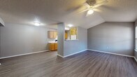 This single-story residence in Conway, Arkansas, offers a practical and comfortable layout designed for everyday living. The open living and dining area serves as the heart of the home, featuring durable wood-look laminate flooring, neutral gray walls, a textured ceiling, and a ceiling fan that enhances airflow throughout the space. Vaulted ceiling lines in the living area add a sense of height and openness, while a pass-through window connects seamlessly to the kitchen.

The galley-style kitchen is efficiently arranged with warm honey-toned wood cabinetry lining both sides, light-speckled countertops, and white appliances including a range, refrigerator, and dishwasher. A range hood and recessed overhead lighting keep the workspace bright and functional.

The bedrooms are carpeted for comfort, each equipped with ceiling fans and windows that allow natural light to filter in. The primary bedroom features dual closets, providing generous storage. Additional bedrooms include individual closets as well.

The bathrooms are finished with matching wood cabinetry, speckled countertops, and integrated sinks. One bathroom includes a full tub-shower combination with overhead storage cabinetry, while another showcases a wide vanity with a large mirror. Throughout the home, consistent gray tones and white trim create a cohesive, move-in-ready aesthetic.