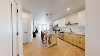 This thoughtfully designed one-bedroom, one-bathroom residence in Longmont, Colorado offers a clean, modern aesthetic throughout its efficiently utilized single-floor layout. Light wood-tone flooring flows seamlessly from the open-concept kitchen and living area, creating a bright and cohesive feel.

The kitchen is a standout feature, showcasing two-tone cabinetry — white upper cabinets paired with warm natural wood lower cabinets — complemented by granite countertops and a full suite of stainless steel appliances. A central island with seating provides additional prep space and a casual dining area, illuminated by a sleek linear pendant light.

The living room opens to a private balcony through a large window, flooding the space with natural light and offering open views of the surrounding Longmont landscape. The bedroom is a calm retreat with a ceiling fan, plush carpet, a generous window with outdoor views, and multiple closets for ample storage.

The bathroom continues the warm, modern palette with a light wood vanity, granite countertop, an undermount sink, and matte black fixtures and hardware. Additional conveniences include in-unit laundry. The overall ambiance is contemporary and airy, with a neutral color palette that maximizes the sense of space throughout.