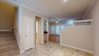 This two-story home is thoughtfully designed with distinct flooring and finishes across each level. The main floor greets visitors with light-toned tile flooring that flows through the entry and kitchen areas, transitioning to warm hardwood in the living spaces. Crown molding runs throughout the main level, adding a refined touch to the neutral-toned walls. A fireplace anchors the living area, while a ceiling fan and large windows with blinds allow natural light to filter in. French doors open to the exterior, enhancing connectivity to the outdoors. The kitchen is equipped with stainless steel appliances, dark granite countertops, light wood cabinetry, and a louvered pantry door for added storage.

A staircase with a glass block accent detail connects the two floors. Upstairs, the bedrooms feature plush carpeting and vaulted ceilings with ceiling fans. The primary bedroom includes mirrored sliding closet doors and a skylight that bathes the room in natural light. An additional carpeted bedroom offers a window with ample natural light. The bathroom includes tile flooring, a glass-enclosed shower and tub combination, dark granite vanity, and light wood cabinetry.