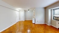 Located on the fourth floor at 2420 16th St NW in Washington, DC's vibrant 16th Street Heights neighborhood, Unit 410 is a well-appointed residence offering a thoughtfully organized layout across a single floor. The living room is bright and open, showcasing warm, richly toned parquet flooring in a classic basket-weave pattern that extends throughout the main living areas. Natural light filters in through a large window, complemented by a ceiling fan that adds both function and character. A radiator along the wall hints at the building's established architectural heritage. The kitchen is efficiently designed with warm wood cabinetry, white countertops, a stainless steel sink, and a window that brings in additional natural light — providing a pleasant and practical cooking space. The bathroom carries a timeless aesthetic, featuring black-and-white mosaic tile flooring, white subway-style wall tiles accented with black trim, a full bathtub with shower, a vanity with under-sink storage, and a mirror cabinet. The walk-in closet is generously proportioned, complete with built-in shelving, a full-length hanging rod, and the same warm parquet flooring, offering excellent storage and organization potential. This unit combines classic details with functional living in one of DC's well-connected urban neighborhoods.