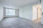 This single-floor, one-bedroom, one-bathroom unit offers a functional and efficiently organized layout across a compact but well-utilized footprint. The combined kitchen and living room serves as the heart of the unit, featuring a galley-style kitchen with white cabinetry, dark granite-look countertops, a gas range, refrigerator, and a stainless steel sink — all set on light tile flooring. A pass-through window with a breakfast bar countertop connects the kitchen to the living area, adding openness and convenience. The living room is carpeted and illuminated by natural light streaming through a large window with vertical blinds, creating a bright and welcoming atmosphere. A ceiling fan enhances comfort in the dining area adjacent to the kitchen pass-through. The bedroom is a generously sized room with plush carpet, a sliding-door closet offering ample storage, and a window with blinds that brings in natural light. The full bathroom is clean and straightforward, featuring a tiled shower-tub combo, a toilet, vanity with mirror, and overhead ventilation. A hallway connects the main living spaces to the bedroom and bathroom, contributing to a logical and private flow throughout the unit.