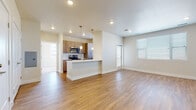 This single-floor residence features a thoughtfully designed open-concept layout connecting the living area and kitchen. The living space is finished with warm hardwood-style flooring and recessed lighting, creating a bright, welcoming atmosphere. Large windows fitted with horizontal blinds allow generous natural light to fill the room, while a sliding door provides additional access and ventilation.

The kitchen is well-appointed with medium-toned wood cabinetry, stainless steel appliances including a range, microwave, and refrigerator, and a clean white countertop peninsula that doubles as a breakfast bar. Pendant lights hang above the peninsula, adding a modern touch. A tile backsplash complements the cabinetry and contributes to the kitchen's contemporary aesthetic.

The bedrooms feature plush neutral carpeting and are served by natural light through sizable windows with blinds. At least one bedroom includes access to a dedicated walk-in closet, providing excellent storage. A ceiling fan enhances comfort in one of the bedrooms.

The bathroom is clean and functional, featuring a wood-tone vanity with a white countertop, a large mirror, hardwood-style flooring, and a shower-tub combination. Throughout the unit, neutral wall tones and consistent finishes create a cohesive, modern ambiance.