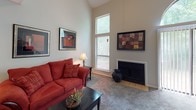 This two-story, 2-bedroom, 2-bathroom home offers a thoughtfully designed layout that maximizes both functionality and comfort. The living room immediately stands out with its soaring vaulted ceilings and tall windows that allow natural light to pour in. A tile-surround fireplace serves as a focal point, lending warmth to the space, which is finished with plush carpeting throughout.

The kitchen features warm wood cabinetry, white appliances including a refrigerator and dishwasher, and light countertops. A pass-through window connects the kitchen directly to the dining area, creating an open, communicative flow between the two spaces — ideal for everyday living and entertaining.

Both bedrooms are generously sized, carpeted, and equipped with ample closet space. The second floor adds a charming loft-style area with sloped ceilings, carpeted flooring, and wall sconce lighting, offering a cozy nook for relaxing or reading.

Each of the two full bathrooms is finished with wood-look luxury vinyl plank flooring, warm wood vanity cabinetry, and white countertops. One bathroom includes a full tub/shower combination. The overall palette throughout the home is neutral and clean, with light gray walls and consistent finishes that create a cohesive, move-in-ready aesthetic.