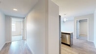 Located at 15 Cooper's Town Road in Winnipeg, this single-floor, three-bedroom residence offers a well-organized layout with a clean, contemporary design throughout. The combined kitchen and living room serves as the heart of the home, featuring a striking blue-accented island with a white countertop, white upper cabinetry, a tile backsplash, stainless steel appliances including a refrigerator, microwave, and dishwasher, and elegant pendant lighting — all set atop light wood-tone flooring. The living area extends to a private balcony through a sliding glass door, inviting natural light into the space. Three bedrooms provide comfortable accommodations; the primary bedroom is generously proportioned and includes a dedicated closet with built-in wire shelving. Additional bedrooms feature plush carpeting and built-in closets with bifold doors. One bedroom showcases light hardwood flooring and a bright window. A dedicated walk-in closet with multi-tier wire shelving adds practical storage. The full bathroom includes a soaker tub with a clean, all-white surround. A central hallway connects all rooms efficiently, and the neutral grey-and-white palette throughout creates a bright, cohesive ambiance well-suited for comfortable everyday living.