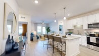 Located at 12525 Tibbets Lane in Jacksonville, FL, this thoughtfully designed 2-bedroom, 2-bathroom residence offers a clean, contemporary aesthetic across a single floor. The open-concept kitchen and living area serves as the heart of the home, where light wood-style flooring, recessed lighting, and white cabinetry create a bright and welcoming atmosphere. The kitchen features granite countertops, a tile backsplash, stainless steel appliances, and a peninsula island with pendant lighting and bar seating — ideal for casual dining or entertaining. The living room extends naturally from the kitchen, offering access to the outdoors through a glass door framed by large windows that invite natural light. Both bedrooms are carpeted and comfortably proportioned, with the primary bedroom featuring an en-suite bathroom complete with a double granite-top vanity, a glass-enclosed walk-in shower, and wood-style flooring. A spacious walk-in closet with wire shelving adds to the primary suite's functionality. The second bathroom mirrors the same refined finishes. A dedicated laundry room with a full-size washer and dryer adds everyday convenience. Two closets throughout the residence provide ample storage, completing this well-rounded and functional home.