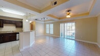 This single-floor residence offers a thoughtfully designed layout that balances open communal spaces with comfortable private quarters. The heart of the home is a bright, open-concept living and dining area finished with large-format ceramic tile flooring and distinctive tray ceilings accented by warm yellow tones. A ceiling fan with a light fixture adds both function and character, while a sliding glass door opens to an outdoor balcony, flooding the space with natural light and providing outdoor access.

The kitchen is well-equipped with rich dark-stained cabinetry, granite countertops, and a full suite of stainless steel appliances, including a refrigerator, range with over-the-range microwave, and dishwasher. A breakfast bar peninsula with pendant lighting connects the kitchen seamlessly to the living area.

The bedrooms feature plush wall-to-wall carpeting, crown molding, ceiling fans, and generous windows that invite natural light. Each room offers a calm, neutral palette well-suited for relaxation.

Two full bathrooms mirror each other in design, each outfitted with tile flooring, a tub-shower combo with full tile surround, a dark-cabinetry vanity topped with granite, and a separate water closet. The cohesive finishes throughout the space create a polished, move-in-ready atmosphere.