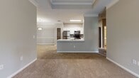 This single-story residence in Buford, Georgia offers a well-designed, open-concept layout that connects the living and dining areas to a centrally positioned kitchen. The kitchen is a functional highlight of the home, featuring white shaker-style cabinetry, light countertops, gray subway tile backsplash, wood-look flooring, and a full suite of stainless steel appliances including a refrigerator, microwave, range, and dishwasher. A peninsula with a built-in sink adds prep space and a natural division between the kitchen and the adjoining living area. The living space is accented by a tray ceiling with crown molding, adding architectural interest and a sense of height to the room.

The bedrooms are carpeted and neutral in tone, offering comfortable, versatile spaces. One bedroom features a tray ceiling with crown molding, while another includes a ceiling fan and a window that brings in natural light. The bathrooms include a full bath with a soaking tub, tiled surround, and curved shower rod, as well as a second bath featuring wood-look flooring, a wide vanity with a white countertop, and ample mirror space. Throughout the home, a consistent neutral color palette and clean finishes contribute to a cohesive, move-in-ready aesthetic.