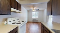 Located in Spokane, WA, this single-floor unit offers a practical and comfortable layout designed for everyday living. The kitchen is well-equipped with dark wood cabinetry providing ample storage, light countertops, a double-coil electric range, a dishwasher, and a stainless steel sink. A range hood and upper cabinets keep the space organized, while hardwood-style flooring extends throughout the kitchen and adjoining dining area. The dining area is brightened by a window with outdoor views and features a ceiling fan with light fixture, along with a wall-mounted HVAC unit for year-round climate control. The spacious living room is carpeted and filled with natural light from large sliding glass doors that open directly onto a private balcony, offering views of surrounding trees. Two bedrooms feature plush carpet, baseboard heating, and windows that bring in natural light, creating a calm and restful atmosphere. The full bathroom includes a tiled tub and shower combination, a single-sink vanity with wood cabinetry, hardwood-style flooring, and clean white walls. A textured ceiling is consistent throughout the unit, contributing to its classic residential character. This well-maintained space offers a functional floor plan suited for comfortable daily living.