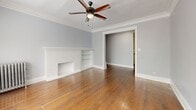 Located in Chicago's Edgewater neighborhood, this two-story home offers four bedrooms, two bathrooms, and a well-appointed layout across two floors. The upper level showcases rich hardwood flooring throughout, complemented by soft grey walls, elegant crown molding, and generous natural light from large windows. The spacious primary bedroom provides a comfortable retreat, while additional bedrooms are well-sized and versatile. The upper-floor kitchen features white shaker cabinetry, granite countertops, a classic subway tile backsplash, stainless steel appliances including a dishwasher, and hardwood floors — a clean, modern aesthetic with timeless appeal. The upper bathroom is finished with full subway tile surrounds and a soaking tub with a window for natural light. The living room is a standout, featuring a decorative brick fireplace with built-in shelving, crown molding, a ceiling fan, and warm hardwood floors. The lower floor offers additional flexible living space with light wood-look tile flooring and a second bathroom finished with subway tile walls, a glass-enclosed shower, and hexagonal mosaic tile flooring — a stylish and practical layout suited for a variety of living arrangements.