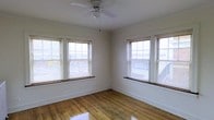 This single-floor space offers a straightforward and functional layout that makes efficient use of its footprint. The interior is finished with warm hardwood floors that run throughout, lending a classic and timeless character to the space. Natural light is a defining feature, with multiple windows — fitted with horizontal blinds — positioned along the walls to allow abundant daylight to fill the room from multiple directions. The white-painted walls keep the interior feeling clean, open, and neutral, providing a versatile backdrop suitable for a variety of uses. A ceiling fan with an integrated light fixture is centrally mounted, contributing to both air circulation and ambient lighting. The windows feature traditional framing and low sills, consistent with a building of established age and character. Crisp white baseboards trim the perimeter of the room, adding a neat, finished touch. The overall ambiance is bright and airy, with a simple, uncluttered aesthetic that highlights the quality of the existing finishes. The space presents well as a blank canvas, offering practical bones and natural light as its primary strengths.