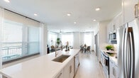 Located at 241 S Chitalpa St in Leander, TX, this single-story, 2-bedroom, 2-bathroom home offers a thoughtfully designed open-concept layout filled with natural light. The heart of the home is a sleek, modern kitchen featuring gray shaker-style cabinetry, subway tile backsplash, stainless steel appliances, and a large quartz waterfall island with an undermount sink and bar seating — ideal for both cooking and entertaining. The kitchen flows seamlessly into a bright dining area and an inviting living room, where large windows, sheer curtains, and a ceiling fan create a comfortable, airy atmosphere. Light wood-look flooring runs throughout the main living areas, adding warmth and continuity. The dedicated dining space is framed by a generous window and offers room for a full dining set. Both bedrooms are carpeted for comfort and feature ceiling fans and ample natural light. The primary bedroom connects to a well-appointed bathroom with gray cabinetry, a white quartz vanity, a large mirror, and a walk-in glass shower with tile surround. The hallways are clean and well-lit, with louvered closet doors adding a modern touch. Each room reflects a cohesive, contemporary design aesthetic throughout.