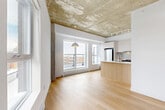 Located at 2600 Cavendish Boulevard in Montréal's NDG neighbourhood, this 1-bedroom, 1-bathroom condo offers a thoughtfully designed layout with a blend of industrial and contemporary finishes. The open-concept kitchen and living area serves as the heart of the unit, featuring striking exposed concrete ceilings that add an industrial character, contrasted by warm light hardwood flooring throughout. Exposed concrete columns further reinforce the architectural identity of the space.

The kitchen is well-appointed with flat-panel cabinetry in a warm off-white tone, stainless steel appliances including a full-size refrigerator and electric range, a built-in dishwasher, and a kitchen island with a white quartz countertop and integrated sink. Large windows and a sliding glass door to the balcony flood the living area with natural light and provide open city views.

The bedroom is a bright, comfortable space with a large window overlooking the cityscape, light hardwood floors, built-in sliding closet doors, and the same exposed concrete ceiling detail. A hallway connects the rooms and leads to the clean, modern bathroom, which features large-format tile flooring, a wall-mounted vanity with a mirrored medicine cabinet, and a full bathtub with tiled surround.
