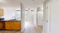 Located at 2 N Main St in Beacon Falls, Connecticut, this two-floor residence offers a well-organized layout across a spacious main level and a functional upper level. The main floor hosts the majority of the living space, including a kitchen equipped with light maple cabinetry, dark granite countertops, stainless steel appliances — including a refrigerator, microwave, and range — and stone-tile flooring. A peninsula counter provides a natural transition into the adjacent living area, which features light hardwood-style flooring and neutral gray walls that carry a clean, consistent aesthetic throughout the home. Two hallways connect the key areas of the main floor, contributing to a smooth flow between spaces. Two full bathrooms are present in the residence, each featuring a tub-shower combination, stone-tile flooring, a wood-toned vanity, and brushed nickel fixtures. The upper level contains the private bedroom, a cozy yet practical space with vaulted ceilings that add a sense of height, light laminate flooring, a built-in closet with sliding panel doors, and a tall window that fills the room with natural light and views of surrounding greenery. The overall ambiance is clean, modern, and move-in ready.