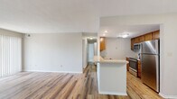This single-floor, 2-bedroom, 2-bathroom residence offers a functional and comfortable layout designed for everyday living. The open-concept kitchen and living area form the heart of the home, where warm-toned wood-look flooring flows throughout. The kitchen features stainless steel appliances — including a refrigerator, range, and microwave — complemented by warm wood cabinetry, a double sink, and a peninsula counter that provides additional workspace and a natural connection to the living area. The living room is bright and spacious, highlighted by a tile-surround fireplace and large sliding glass doors with vertical blinds that invite natural light and provide outdoor access. Both bathrooms are finished with white tile tub-shower surrounds, chrome fixtures, and wood-toned vanities with light countertops. The primary bedroom is generously sized, featuring plush carpet and a large walk-in closet equipped with dual wire shelving for ample storage. The second bedroom is also carpeted and benefits from a large window with natural views. A dedicated closet and consistent neutral tones throughout lend the space a clean, cohesive aesthetic well-suited for comfortable residential living.