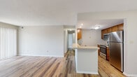 This single-floor, 2-bedroom, 2-bathroom residence offers a functional and comfortable layout designed for everyday living. The open-concept kitchen and living area form the heart of the home, where warm-toned wood-look flooring flows throughout. The kitchen features stainless steel appliances — including a refrigerator, range, and microwave — complemented by warm wood cabinetry, a double sink, and a peninsula counter that provides additional workspace and a natural connection to the living area. The living room is bright and spacious, highlighted by a tile-surround fireplace and large sliding glass doors with vertical blinds that invite natural light and provide outdoor access. Both bathrooms are finished with white tile tub-shower surrounds, chrome fixtures, and wood-toned vanities with light countertops. The primary bedroom is generously sized, featuring plush carpet and a large walk-in closet equipped with dual wire shelving for ample storage. The second bedroom is also carpeted and benefits from a large window with natural views. A dedicated closet and consistent neutral tones throughout lend the space a clean, cohesive aesthetic well-suited for comfortable residential living.