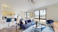 This contemporary two-story residence in Berkeley, California offers a thoughtfully designed layout spread across two levels, blending modern finishes with an abundance of natural light. The welcoming entryway features warm wood-tone flooring and a sleek staircase with black metal railings that leads to the upper level, setting a clean, modern tone throughout.

The open-concept living area is bright and airy, anchored by large floor-to-ceiling windows that frame views of the surrounding neighborhood and nearby palm trees. The kitchen is efficiently laid out with light wood cabinetry, dark stone countertops, white appliances, and a peninsula that defines the dining area — complete with a compact dining table and seating.

The bedrooms are generously proportioned and carpeted for comfort, each benefiting from large windows that invite natural light and offer pleasant views of the Berkeley skyline and treetops. The upper-level bedroom features a serene, neutral palette, while a second bedroom comfortably accommodates multiple beds.

The bathrooms are finished with stone-look countertops, light wood vanities, wood-tone flooring, and glass-enclosed shower enclosures, offering a clean and functional design. Located in the heart of the East Bay, this residence combines modern architecture with practical living in a well-connected neighborhood.