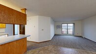 Located at 11719 Champlin Drive in Champlin, MN, this 2-bedroom, 1-bathroom unit offers a practical and well-organized single-floor layout. The open kitchen and living area forms the heart of the unit, featuring a galley-style kitchen equipped with warm oak cabinetry, ample counter space, white appliances including a refrigerator, range, and dishwasher, and tile flooring. A peninsula counter separates the kitchen from the living area, which transitions to carpet and leads to a sliding glass door opening onto a balcony, allowing for natural light and outdoor views. The spacious living room also features a wall-mounted air conditioning unit and baseboard heating. Both bedrooms are carpeted and bright, each with a window fitted with vertical blinds and baseboard heating. The primary bedroom includes a closet with built-in shelving. The full bathroom features an oak vanity with generous counter space, a large mirror, and tile flooring. A textured ceiling is consistent throughout the unit, and warm wood-toned trim and doors add a cohesive, classic feel to the overall interior. Two closets provide additional storage throughout the unit.