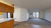 Located at 11719 Champlin Drive in Champlin, MN, this 2-bedroom, 1-bathroom unit offers a practical and well-organized single-floor layout. The open kitchen and living area forms the heart of the unit, featuring a galley-style kitchen equipped with warm oak cabinetry, ample counter space, white appliances including a refrigerator, range, and dishwasher, and tile flooring. A peninsula counter separates the kitchen from the living area, which transitions to carpet and leads to a sliding glass door opening onto a balcony, allowing for natural light and outdoor views. The spacious living room also features a wall-mounted air conditioning unit and baseboard heating. Both bedrooms are carpeted and bright, each with a window fitted with vertical blinds and baseboard heating. The primary bedroom includes a closet with built-in shelving. The full bathroom features an oak vanity with generous counter space, a large mirror, and tile flooring. A textured ceiling is consistent throughout the unit, and warm wood-toned trim and doors add a cohesive, classic feel to the overall interior. Two closets provide additional storage throughout the unit.