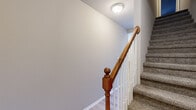 This multi-level home spans three floors, offering a thoughtfully distributed layout across its levels. The entry floor provides an inviting introduction to the space, featuring light hardwood-style flooring that continues into the main living area, which benefits from large windows and a sliding glass door that fills the room with natural light and offers views of the outdoors.

The kitchen is well-equipped with warm honey-toned wood cabinetry, granite countertops, stainless steel appliances including a range, built-in microwave, and dishwasher, all set atop easy-care hardwood-style flooring. A double sink with a sleek faucet completes this practical and attractive cooking space.

The bathrooms carry a consistent aesthetic, featuring granite-topped wood vanities, tile flooring, and well-lit mirrors. Each provides a clean, functional design suited to everyday use.

The two bedrooms are carpeted for comfort, with the spacious primary bedroom featuring vaulted ceilings and multiple windows that invite generous natural light and outdoor views. The secondary bedroom also benefits from a large window with vertical blinds.

Throughout the home, the staircases are finished with carpet treads and classic wooden banisters with white balusters, lending a timeless character to the transitional spaces. The neutral gray wall palette ties each level together cohesively.