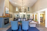 Located in the heart of San Jose's Willow Glen neighborhood, this thoughtfully designed community space offers a warm and inviting atmosphere across a single, well-appointed floor. The centerpiece is a dramatic great room with soaring vaulted ceilings and a striking arched window that floods the interior with natural light. Elegant chandelier lighting complements the bright, airy ambiance, while light hardwood-style flooring flows throughout the space.

The lounge area is generously furnished with plush sofas, accent chairs, and a rustic wooden coffee table, arranged to encourage conversation and relaxation. Built-in wooden bookshelves flank the main seating area, adding warmth and a library-like character. A tiled fireplace with a teal geometric surround anchors one corner of the room, accompanied by a dining table and curated botanical wall art.

A reception area near the entrance features a marble-topped table and a service window, offering a functional transition zone. Adjacent to the main lounge, a fully equipped kitchen presents crisp white cabinetry, stainless steel appliances, a decorative patterned tile backsplash, and a skylight that draws in additional natural light. Double doors open directly to the outdoors, connecting the interior seamlessly to the surrounding landscape of this vibrant Willow Glen community.