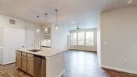 This thoughtfully designed 2-bedroom, 2-bathroom residence offers a comfortable and functional single-floor layout. The heart of the home is an open-concept living, dining, and kitchen area, where rich hardwood-style flooring flows seamlessly throughout. The kitchen is a standout feature, equipped with a large central island topped with granite countertops, warm wood cabinetry, stainless steel appliances including a refrigerator, range, microwave, and dishwasher, and elegant pendant lighting overhead. The living area benefits from large windows that invite natural light and a ceiling fan for added comfort.

Both bedrooms are carpeted and generously sized, each featuring ceiling fans or ample lighting and access to closet space. The primary bedroom connects to its own bathroom and includes a spacious walk-in closet with built-in shelving and hanging rods. The two bathrooms are finished with granite vanity countertops and wood-toned cabinetry; one features a full tub-shower combo with classic white subway tile surround. Additional highlights include six closets for exceptional storage, a dedicated laundry area, a utility room, and consistent neutral tones throughout that create a clean, modern aesthetic.