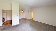 This well-appointed two-bedroom, two-bathroom residence in Lansing, Michigan offers a thoughtfully organized single-floor layout with a comfortable sense of space throughout. The open-concept living and dining area serves as the heart of the home, featuring soft carpet flooring, a ceiling fan, and vaulted ceilings that add an airy feel. A sliding glass door leads directly to a private balcony, bringing in natural light and outdoor views. The kitchen is positioned adjacent to the living area and features warm wood-toned cabinetry, a peninsula with a built-in sink and ample counter space, and essential appliances including a range and microwave. Both bedrooms are carpeted and offer a calm, neutral palette with dedicated closet space. The primary bedroom is generously sized and benefits from its own en-suite bathroom, which includes a standalone shower. The second bedroom features a large window with vertical blinds, filling the room with natural light. A second full bathroom with a tub/shower combination and tile flooring serves guests and the second bedroom. Additional practical features include in-unit laundry and four closets distributed throughout the home for excellent storage capacity. A connecting hallway ties all spaces together in a clean, functional flow.