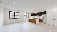 Located at 4614 John F Kennedy Blvd in Union City, NJ, this modern 2-bedroom, 1-bathroom residence offers a thoughtfully designed single-floor layout with clean lines and contemporary finishes throughout. Light gray wood-look flooring runs seamlessly across all rooms, contributing to a cohesive and airy aesthetic.

The open-plan kitchen and living area serves as the heart of the home. The kitchen is outfitted with dark upper cabinetry contrasted by warm wood-toned lower cabinets, a marble-look quartz backsplash and countertops, stainless steel appliances, and a striking center island with a natural wood panel accent and pendant lighting above. A stacked in-unit washer and dryer is conveniently integrated into the kitchen area. Large black-framed windows flood the living space with natural light.

The primary bedroom is a well-proportioned retreat featuring a double closet with black hardware, a wall-mounted split AC unit, and a black-framed window with neighborhood views. The second bedroom also includes a closet and natural light from a similarly styled window. Both rooms maintain the clean white palette found throughout.

The bathroom is elegantly finished with large-format marble-look wall tiles surrounding a tub-shower combination with a glass panel, complemented by warm-toned floor tiles and a wood-accented vanity.