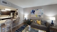 This two-floor residence in Houston, TX offers a well-designed layout across two levels, featuring two bedrooms and one full bathroom. The living room serves as the heart of the home, finished with plush carpeting, neutral gray walls, and large windows that invite natural light and outdoor views. The open connection to the kitchen creates a seamless flow ideal for everyday living and entertaining.

The kitchen is outfitted with dark espresso cabinetry contrasted by light stone-patterned countertops, stainless steel appliances including a refrigerator, range, and built-in microwave, and wood-style flooring. A breakfast bar with seating bridges the kitchen to the living area. Adjacent to the living room, a dedicated dining space features a pendant light fixture overhead, adding an intimate ambiance.

Both bedrooms are carpeted and feature ceiling fans. The primary bedroom offers ample floor space, while the second bedroom provides flexible use. The bathroom includes dark cabinetry, a stone-topped vanity, a large mirror with overhead storage, and wood-style flooring. Neutral tones and consistent finishes throughout create a cohesive, comfortable atmosphere.