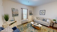 This thoughtfully laid-out unit in Fort Wayne, Indiana offers a comfortable and functional single-floor living experience. The open-concept kitchen and living area form the heart of the space, creating a seamless flow between cooking and relaxing. The kitchen is equipped with white cabinetry, a full-size refrigerator, an electric range, and a central island with a light stone-look countertop and bar seating for multiple guests — ideal for casual dining. Recessed lighting and a pendant fixture above the island add a modern touch, while light wood-tone flooring extends throughout.

The living area is bright and welcoming, featuring a large window dressed with curtains that allows natural light to fill the room. A wall-mounted HVAC unit provides climate control, while the neutral wall palette and warm décor accents create an inviting ambiance. A dedicated seating nook with an additional window adds versatility to the space.

The bathroom is clean and well-appointed, featuring a single vanity with storage, a toilet, and a tub/shower combination, all set on the same wood-tone flooring. A closet provides convenient storage. Throughout the unit, the design is cohesive and move-in ready, making it a practical and comfortable home.