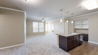 Located at 4 Stadium Dr in Angleton, Texas, this single-story, 2-bedroom, 2-bathroom home offers a well-designed layout with a comfortable and functional living experience. The open-concept living and kitchen area forms the heart of the home, featuring plush carpet, crown molding, and a ceiling fan. The kitchen is outfitted with rich dark-wood cabinetry, granite-style countertops, a tile backsplash, black appliances, hardwood-style flooring, and a center island with a sink and pendant lighting overhead — ideal for both cooking and casual dining. A built-in shelving nook adds additional storage and display space. The spacious primary bedroom includes a ceiling fan, carpet flooring, natural light from a window, and direct access to an en-suite bathroom featuring a granite vanity, white cabinetry, tile flooring, and a shower. The second bedroom is equally bright, with a ceiling fan and windows offering neighborhood views. Four closets throughout the home — including a generously sized walk-in with wire shelving — provide abundant storage. A dedicated laundry room houses full-size washer and dryer units. Additional features include a patio for outdoor relaxation and a hallway connecting all rooms efficiently. The warm neutral palette and crown molding throughout lend a polished, cohesive aesthetic.
