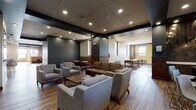 Located at 50 Public Square in the heart of Cleveland, Ohio, this single-floor amenity space offers a well-appointed and thoughtfully designed environment suited for both social gatherings and relaxed downtime. The open lounge area serves as the central hub, furnished with contemporary upholstered sofas and armchairs arranged around wooden coffee tables, all set atop warm hardwood flooring. Recessed lighting and a dark tiled ceiling give the space a refined, modern ambiance, while a wall-mounted flat-screen television adds a functional touch. Adjacent to the lounge, a fully equipped kitchen stands out with rich dark walnut cabinetry, striking herringbone-patterned tile backsplashes, stone countertops, a double wall oven, a large island, and pendant lighting — delivering both elegance and practicality. Intimate booth seating alcoves, finished in leather banquettes and accompanied by small bistro tables with vibrant accent chairs, provide semi-private nooks ideal for conversation. A dedicated game room, filled with natural light from multiple windows, houses shuffleboard and billiards tables atop dark hardwood floors, offering an engaging recreational retreat. Open transitional corridors connect each zone, maintaining a cohesive flow throughout the entire space.